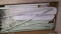 White metal rods, plastic connectors and white fabric storage bag inside the box