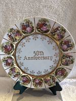 Front view of the commemorative porcelain plate showing 50th Anniversary text, romantic scenes around the edge, and gold detailing.