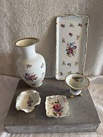 Photo showing entire set with vase, tray, bowls, and dishes on grey surface with floral designs and gold trim.