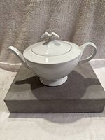 Side view of the white porcelain tea pot showing its elegant shape and decorative lid knob.