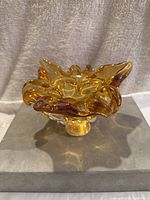 Side angle view of vintage amber glass decorative piece showing ruffled design and warm amber hues.