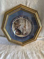 Frontal image showing the porcelain plate mounted in an octagonal gold frame with a domestic scene.