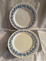 Two Wedgwood embossed Queens Ware porcelain plates, showing blue grapevine pattern and fluted edges