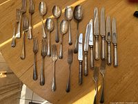 Assorted sterling flatware pieces arranged on a wood surface