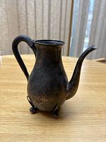 Three-quarter front view showing body, spout and scroll feet