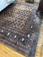 Overhead view of entire rug showing field pattern and border next to sofa.