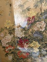 Close-up photo showing detailed floral depiction with multi-colored peonies and leaves under a reflective glass surface.