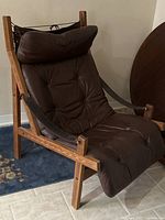 Full view of chair showing wood frame, leather cushions, headrest, sling design