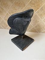 Front view of abstract black stone sculpture on square base