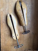 Two vintage wooden shoe stretchers side by side on wooden surface, showing their shape and size.