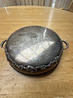 Top view of sterling silver lid on stand showing central monogram and overall surface condition