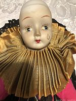 Close-up of porcelain head showing hand-painted facial features and gold pleated collar