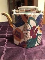 Left side view of hexagonal floral ceramic teapot showing brass spout and pattern