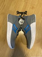 Side view of gray and blue Athletic Works running shoes with white sole and tags attached showing brand and size