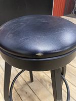 Close-up of the small rip on the black leather seat cushion, showing wear on the front edge.