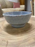 Side view of blue ceramic bowl showing textured horizontal ridges with speckled blue glaze.