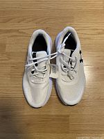 Top view of pair of white Under Armour runners with tags visible, showing mesh upper and lacing.