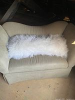 Long white fuzzy rectangular pillow displayed on a beige sofa, showing the full length and texture of the soft fluffy covering.