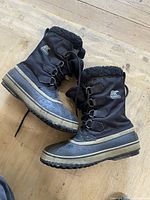 Side view of pair of black Sorel men's winter boots size 8.5, showing laces, material and fleece lining.