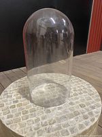 Photo of clear glass globe dome on tiled surface, showing shape and transparency.