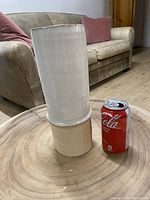 Photo showing the two tone ceramic vase next to a soda can for size reference, set on a wooden surface in front of a sofa.
