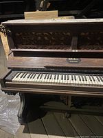 Front view showing full keyboard and ornate carved wood panel with Weber New York nameplate visible.