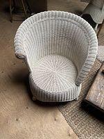 Top view of vintage white wicker chair showing circular seat and round backrest with rolled armrest.