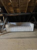 Front view of white upholstered couch with vertical tufted design, boxy arms, and solid base