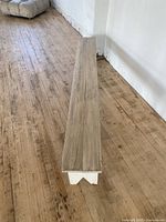 Full length top view of the wooden bench showing the natural wood plank top and white painted leg structure on wooden floor.