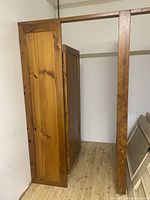 Wooden door panel and frame show natural wood grain and finish, in a light wood tone with visible knots and grain patterns. Positioned standing upright against a wall.