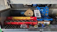 Wide shot showing all tools in metal toolbox, including large red jumbo socket set, coolant tester, automotive balancer, and blue brake service tool kit.