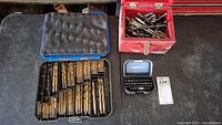 Black plastic case open showing many sizes and types of drill bits organized inside.