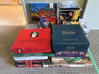 Photo showing stack of boxed family board games and puzzles including Scattergories, Trivial Pursuit, Face to Face, Clue, Life, and a puzzle titled Vancouver Island.