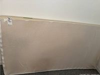 Foam mattress standing upright against a wall, showing full surface area with a tag on the corner.