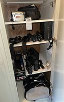 Full view of shelving unit with Sony Handycam, multiple binoculars, tripod, watch, and bags.