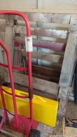 Wooden saw horses in background with red hand trolley and yellow picnic table box in front