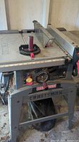 Front view of Craftsman table saw showing blade, blade guard, control dials and stand with brand name.