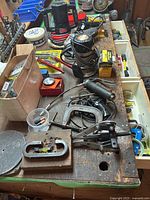 Workbench covered with assorted hand and electric tools, clamps, hand crimper, and hardware boxes