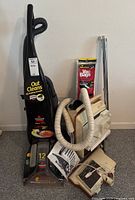 Overview showing Bissell ProHeat upright cleaner, beige canister vacuum with hoses, chrome extension wands and pack of replacement vacuum bags.