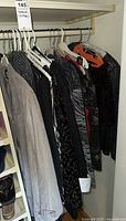 Clothes hung on a rod showing multiple women's jackets and dresses in various dark and neutral tones