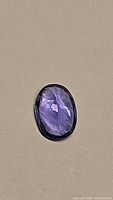 Top view of an oval cut tanzanite gemstone showing deep blue-purple color and faceting details.