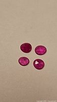 Four natural hot pink sapphires on a plain background, showing different shapes and sizes
