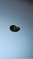 Oval cut natural chameleon green sapphire from Madagascar visible with rich green color and faceting.