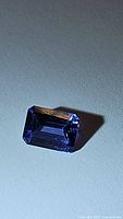 Top view of octagon-cut purple-blue tanzanite gemstone on white background