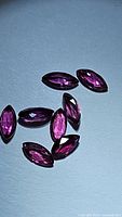 Eight natural untreated marquis cut rubies laid out on a flat surface, showing deep red to hot pink colors and the marquis cut shape.