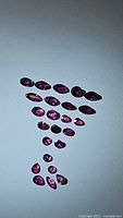 Photo of multiple natural untreated rubies arranged on a white background, showing mixed cuts and sizes.