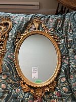 Full frontal view of oval mirror on floral-patterned quilt background