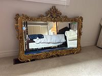 Full view of rectangular gold-painted carved wood framed mirror showing decorative crest and base
