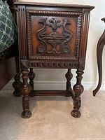 Full front view of nightstand showing carved front door and turned legs