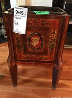 Front view of the wooden plant stand showing floral painted decoration and metal liner inside.